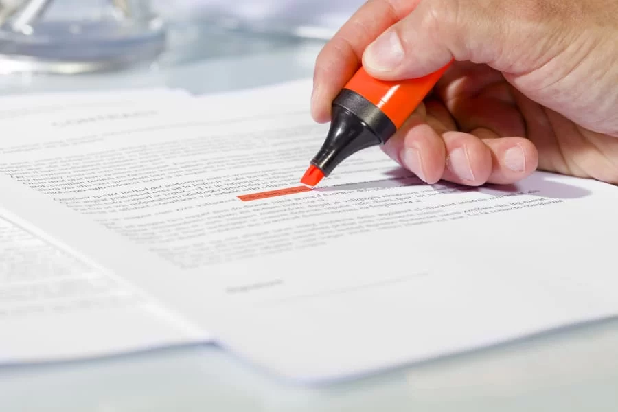 Close-up of man hand with highlighter over document, checking the content before signing
